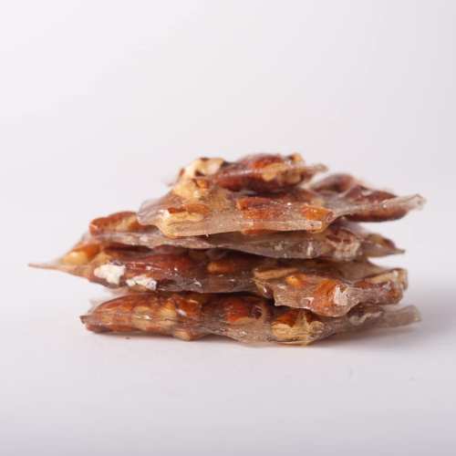 A stack of translucent candy pieces with nuts, showcasing a glossy texture and a mix of brown and clear colors.