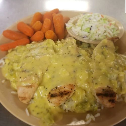 A plate of grilled chicken topped with creamy sauce, served with rice, carrots, and a side of coleslaw.