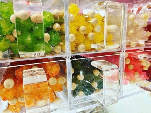 Colorful gummy candies in clear containers, featuring various shapes and vibrant hues like green, yellow, orange, and red.