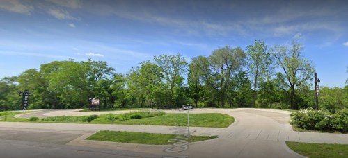 A winding road surrounded by lush green trees under a clear blue sky.