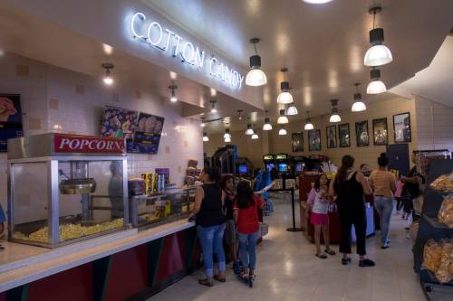A brightly lit concession stand with popcorn and cotton candy, featuring families and children enjoying snacks.