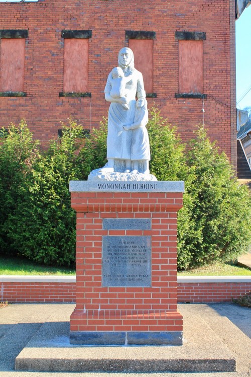 Statue of a woman holding a child, titled "Monongah Heroine," on a brick pedestal with inscriptions.