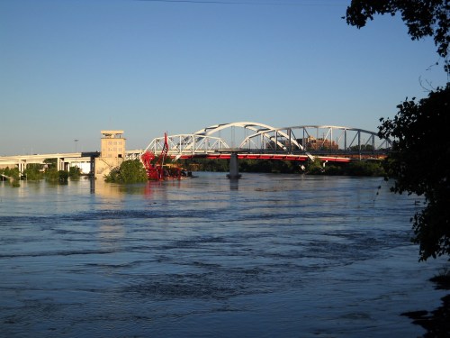 A river scene featuring a bridge, a control tower, and calm water under a clear blue sky.