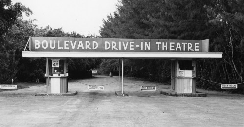 Black and white image of the Boulevard Drive-In Theatre entrance with a large sign and ticket booth.