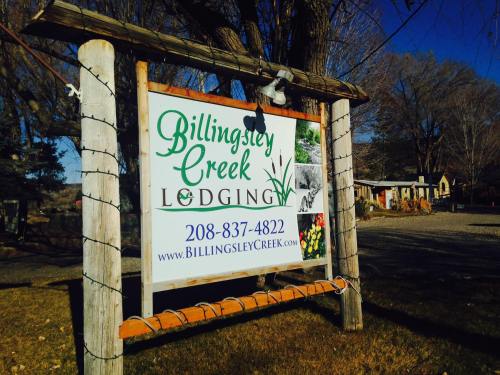 Sign for Billingsley Creek Lodging with contact number, surrounded by trees and a clear blue sky.