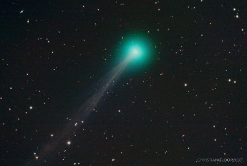 A bright green comet with a long tail, surrounded by a starry night sky.