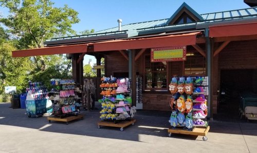 A colorful outdoor shop displaying various flip-flops and beach accessories on racks in front of a wooden building.