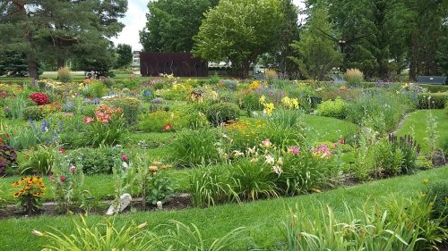 A vibrant garden filled with colorful flowers and lush greenery, surrounded by trees and a serene landscape.