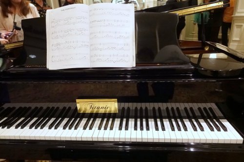 A grand piano with sheet music titled "The Portrait" displayed on top, featuring a "Titanic" nameplate.