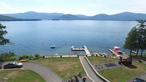 Scenic view of a lake with mountains in the background, a dock, boats, and a playground in the foreground.