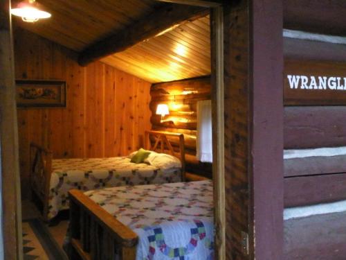 Cozy cabin interior with two beds, wooden walls, and warm lighting, creating a rustic and inviting atmosphere.