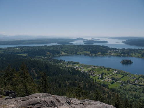A panoramic view of lush green landscapes, lakes, and islands under a clear blue sky.