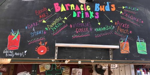 Chalkboard menu featuring colorful drink options: Bloody Mary, Dark & Stormy, Dumpster Punch, Victoria's Cooler, Margaritas, Pirate Punch.