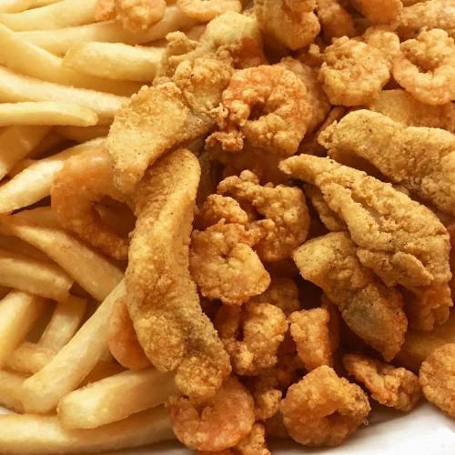A close-up of crispy fried shrimp and golden French fries on a plate.