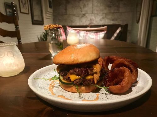 A delicious cheeseburger with crispy onion rings on a plate, set in a cozy dining space.