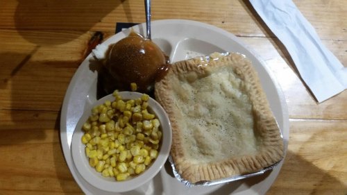A plate with a baked pie, a scoop of ice cream with caramel sauce, and a side of corn.