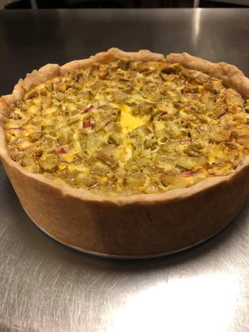 A freshly baked rhubarb pie in a golden crust, resting on a stainless steel surface.