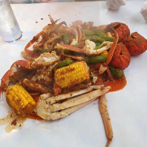 A vibrant seafood platter with crabs, crawfish, corn, and green peppers, served on a white table.