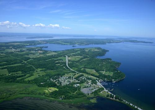 Aerial view of a lush green landscape with water bodies, islands, and a small settlement along the shore.