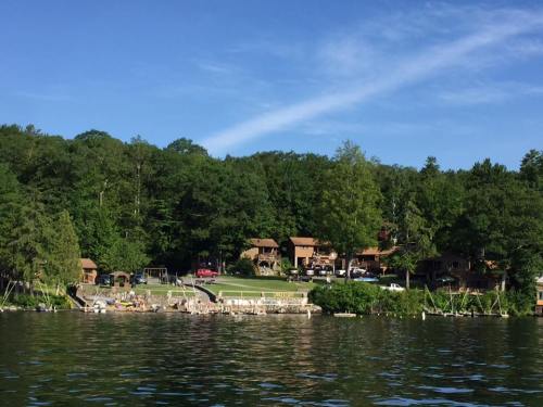 A serene lakeside view featuring a row of cabins nestled among lush green trees.