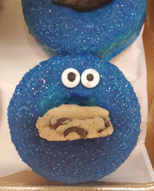 A blue donut with sparkles, featuring eyes and a cookie in its mouth, resembling a cartoon character.