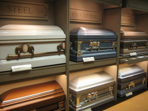 A display of various metal caskets in a funeral home, showcasing different colors and styles.