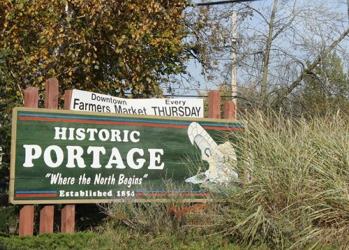 Sign for Historic Portage, featuring "Where the North Begins" and details about the downtown farmers market on Thursdays.