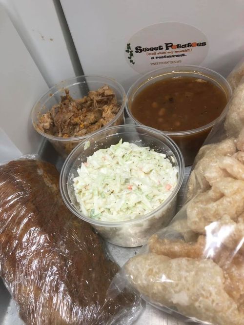 A variety of food items including pulled pork, coleslaw, beans, and pork rinds in clear containers.
