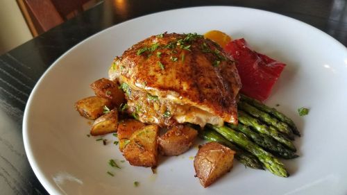A plated dish featuring grilled salmon, asparagus, roasted potatoes, and a colorful garnish.