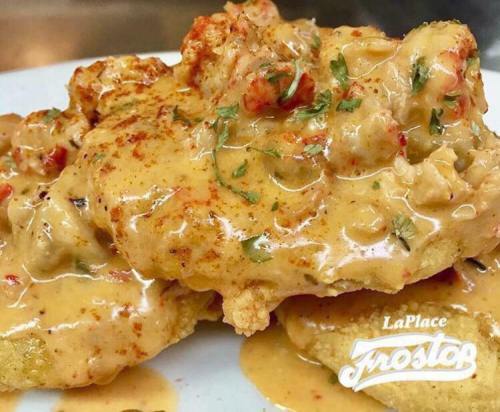Plate of fried seafood topped with a creamy sauce and herbs, served over crispy fried plantains.