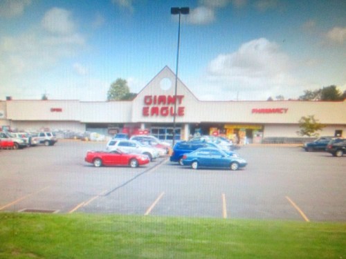 Exterior view of a Giant Eagle supermarket with a pharmacy, featuring a parking lot filled with cars.