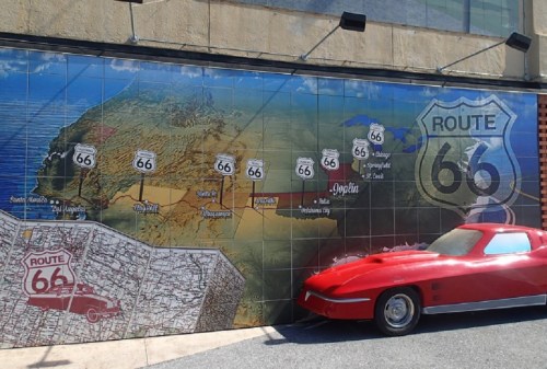 A mural of Route 66 featuring a map and a vintage red car in front of it.