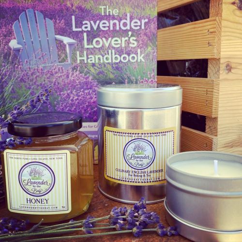 A jar of lavender honey, a tin of culinary lavender, and a candle, with a lavender-themed book in the background.