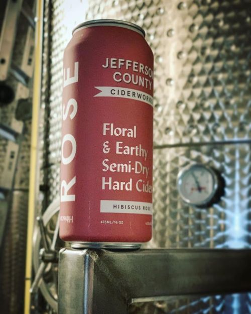 A can of Jefferson County Ciderworks Hibiscus Rose hard cider on a metal surface, with a gauge in the background.