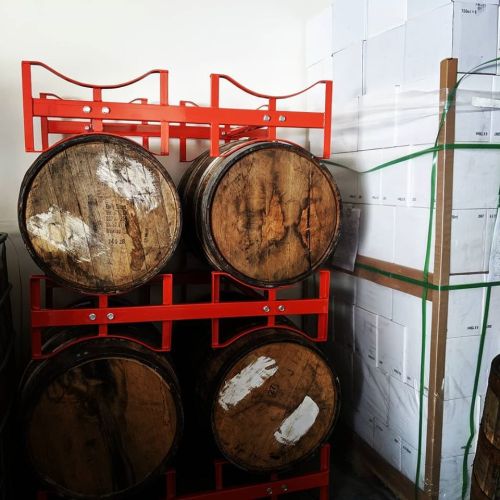 Wooden barrels stacked on a red rack, with white boxes in the background.