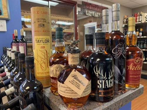 A display of various whiskey bottles, including Colonel E.H. Taylor, Blanton's, and Weller, in a retail setting.
