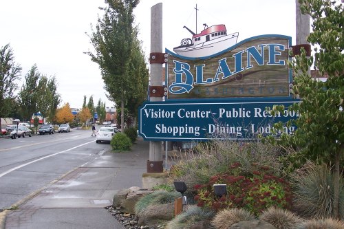 Sign for Blaine, Washington, indicating visitor center, public restrooms, shopping, dining, and lodging along a street.