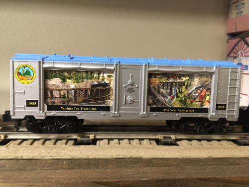 A model train car featuring a detailed diorama inside, celebrating the Wichita Toy Train Club's 25th anniversary.