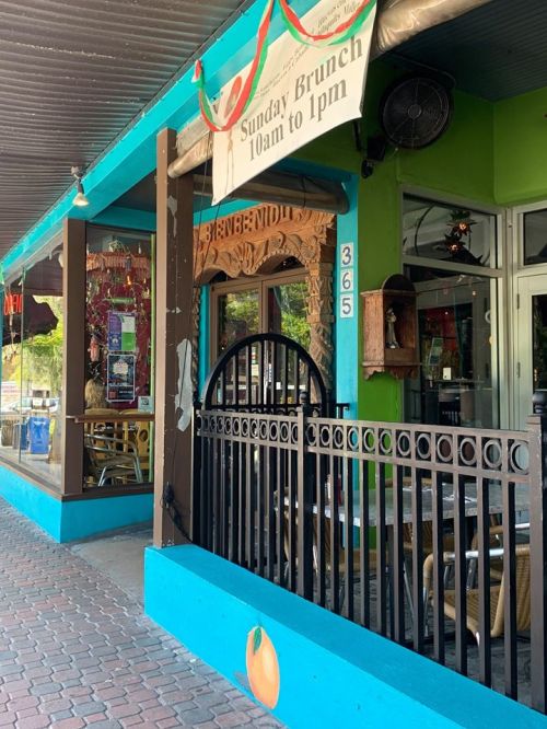 Colorful restaurant exterior with a sign for Sunday brunch, featuring a decorative entrance and outdoor seating.