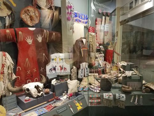 Display of traditional Native American clothing and artifacts in a museum setting, showcasing cultural heritage.