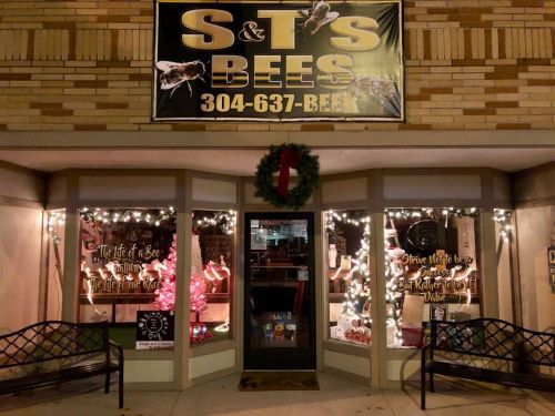 A storefront with a sign reading "S&T's Bees," decorated with lights and a wreath for the holidays.