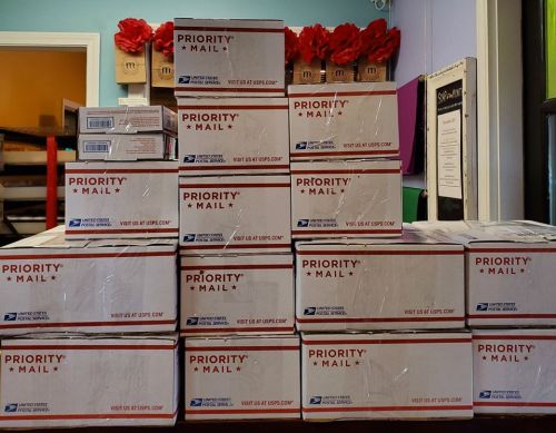 A stack of USPS Priority Mail boxes arranged neatly on a table.