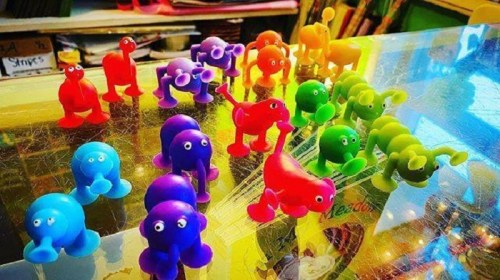 A colorful collection of small, cartoonish animal figures in various shapes and colors arranged on a shiny surface.
