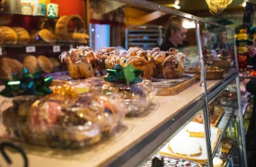 A display case filled with baked goods, including muffins and pastries, with a person working in the background.