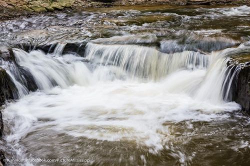 A serene waterfall cascading over rocks, creating a smooth flow of water in a natural setting.