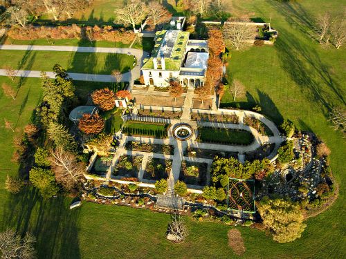 Aerial view of a large estate with manicured gardens, pathways, and a central fountain surrounded by greenery.