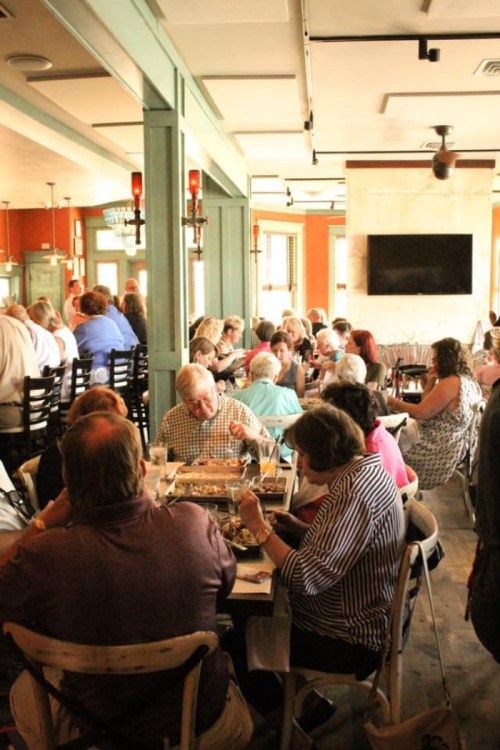 A busy restaurant filled with people dining and socializing at tables, with a warm and inviting atmosphere.