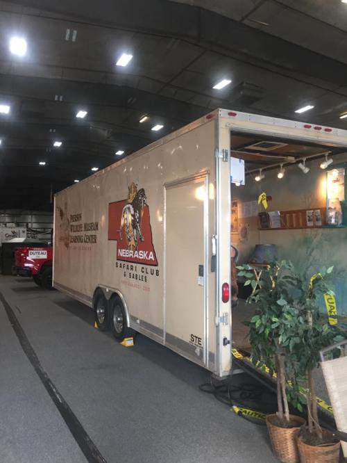 A trailer for the Nebraska Safari Club and Wildlife Museum, displayed indoors with various informational items.