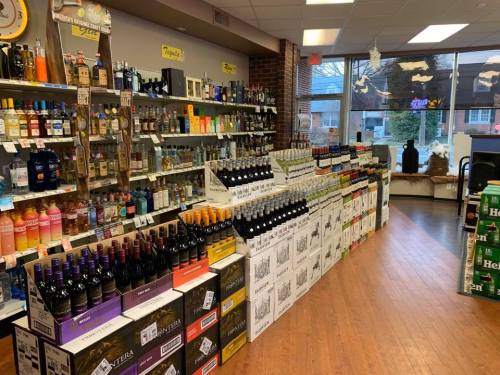 A well-stocked liquor store aisle featuring various bottles of wine and spirits on shelves and displays.