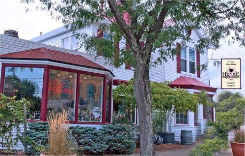 A charming restaurant with a red roof and large windows, surrounded by greenery and signage for Henke Winery.